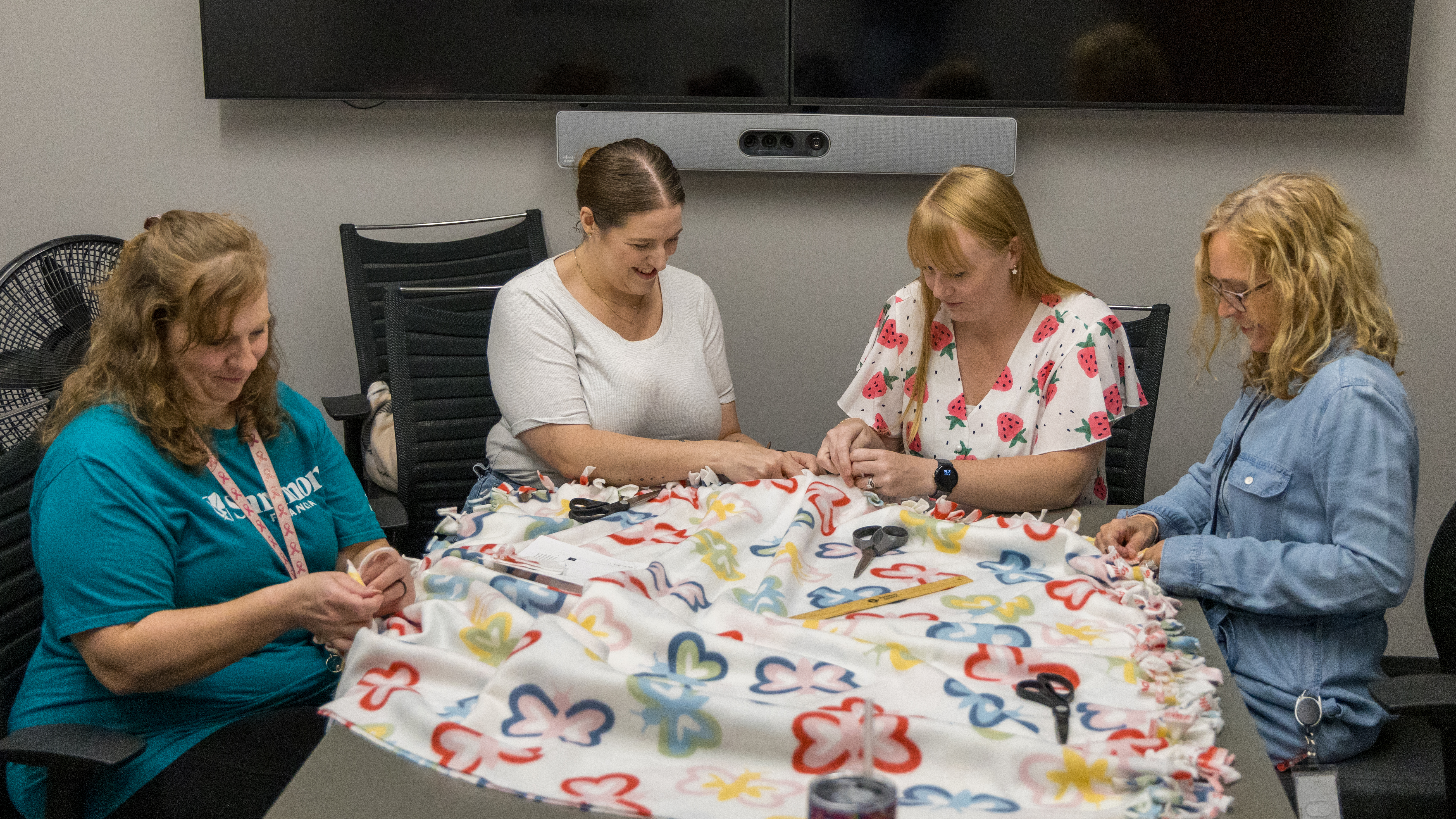 Four Sammons Financial employees making hand tied blankets.